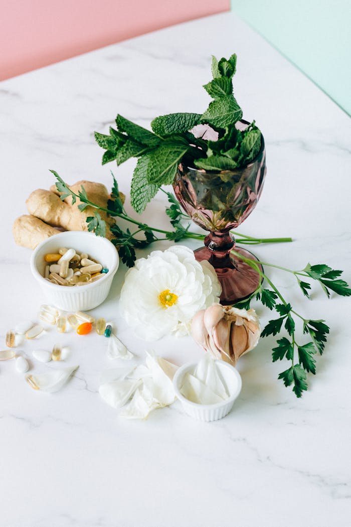 Arrangement of herbal medicine ingredients with capsules on marble surface for natural treatment.